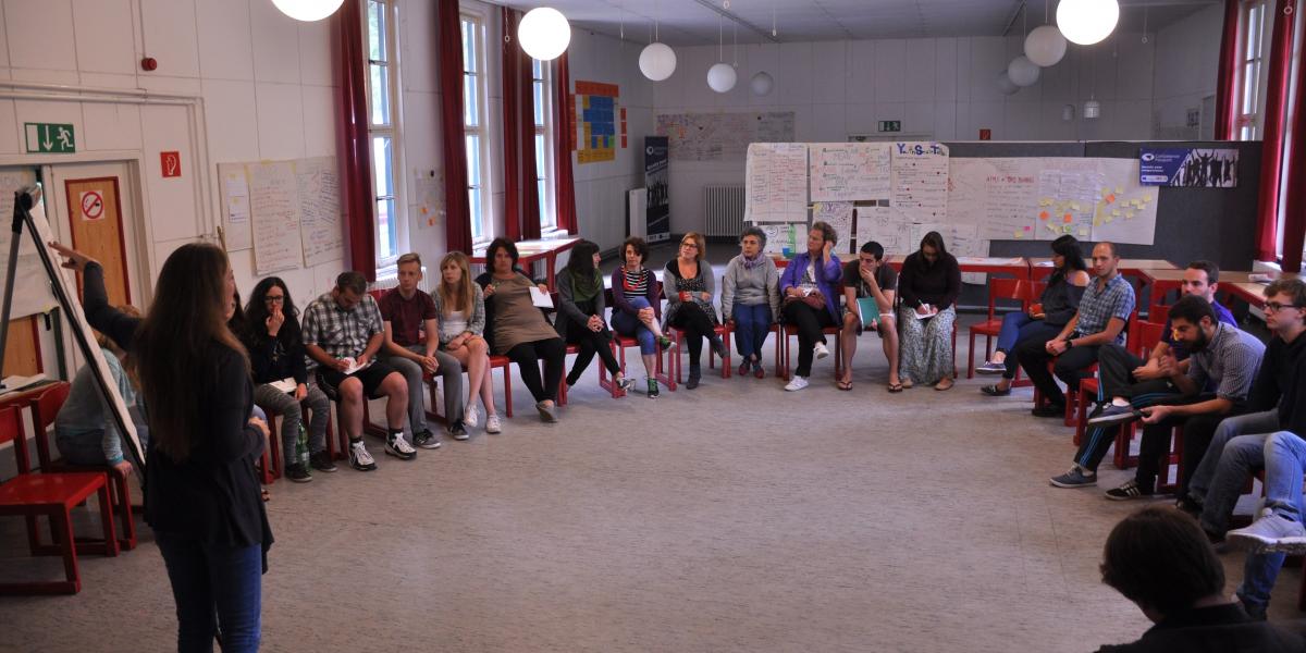 Young people sitting in a circle and listening to a presentation
