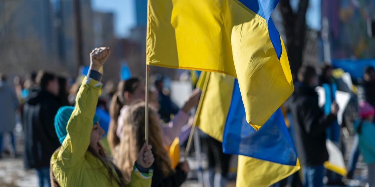Young girl protesting in the street and holding the Ukrainian flag