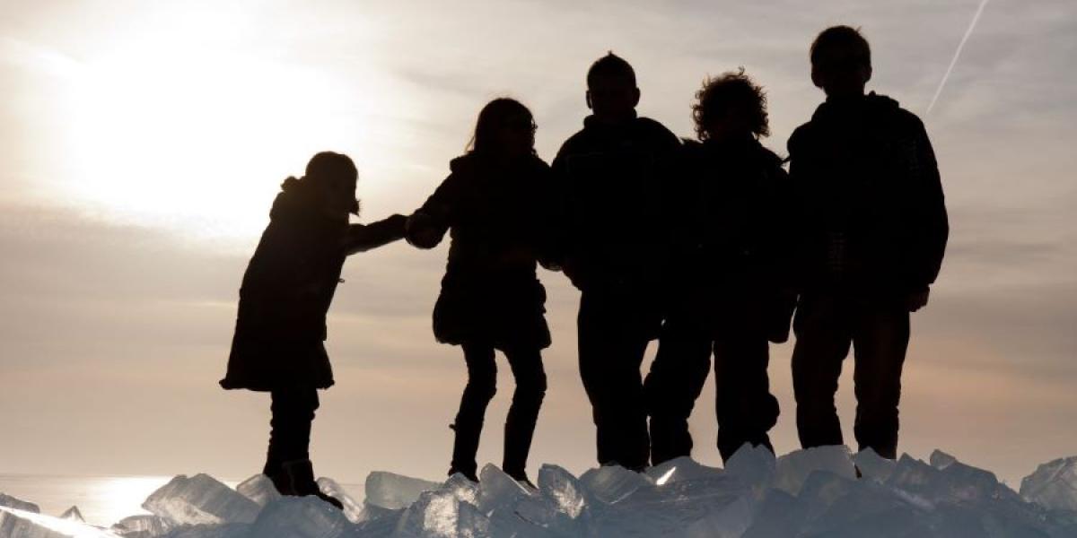 silhouettes of 5 people standing on a glacier