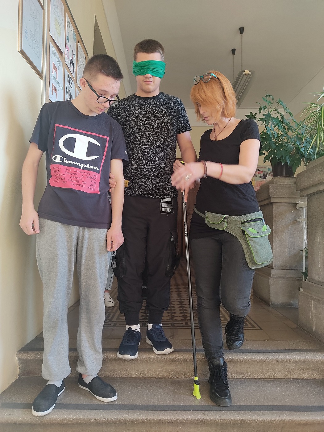 učenik vodič pomaže 'slijepom' učeniku (učeniku povezanih očiju) kretanje po stepenicama pomoću štapa uz pratnju defektologinje