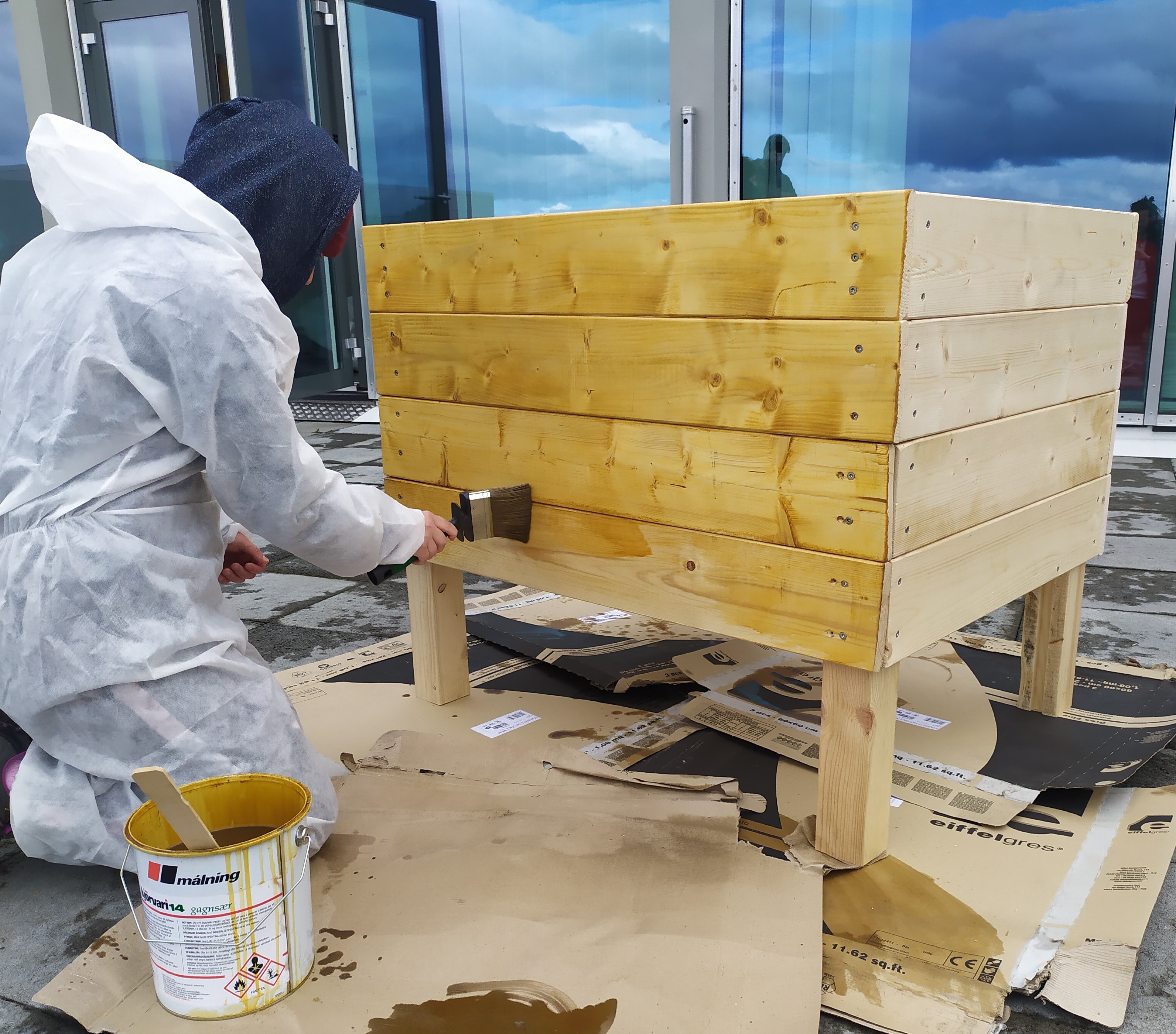 Young person painting a wooden plant pot