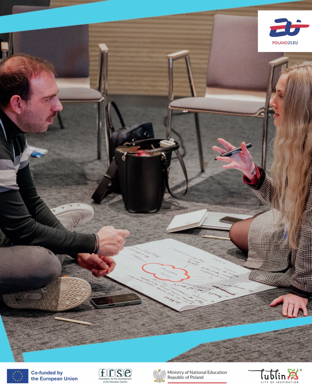 Two people sit on the floor in discussion, surrounded by chairs. They focus on a large sheet of paper with notes and a cloud diagram. A pen and smartphone are nearby. Logos for Poland25.eu, the European Union, and other organisations are visible.