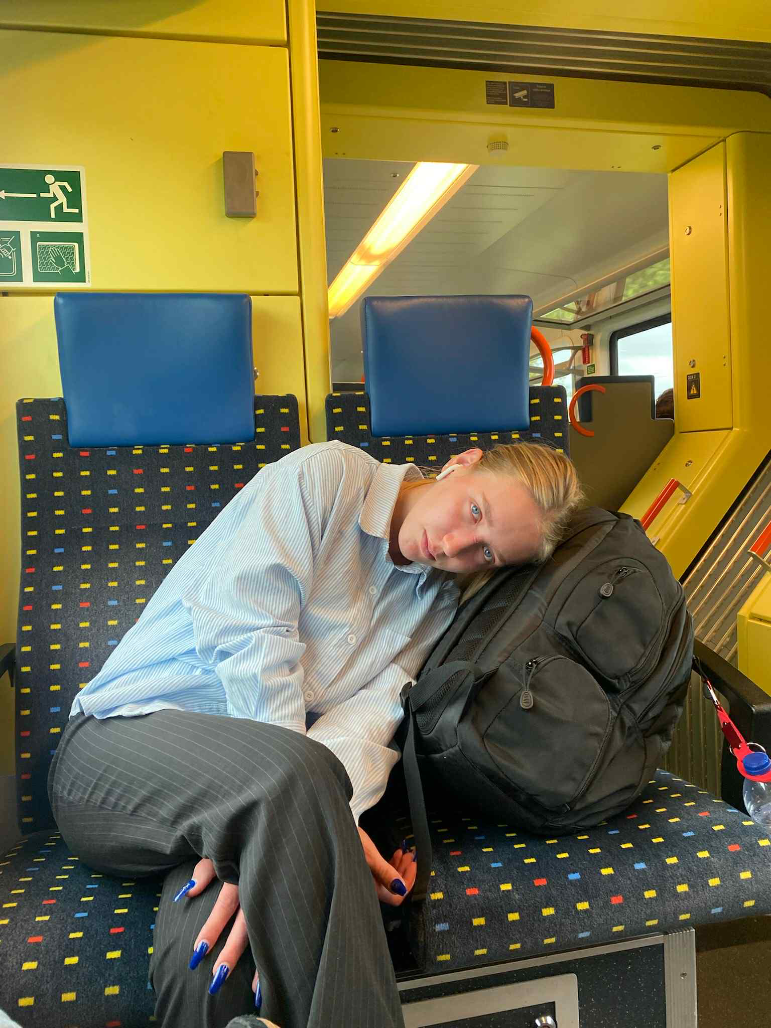 A young person with blonde hair sitting in a train seat