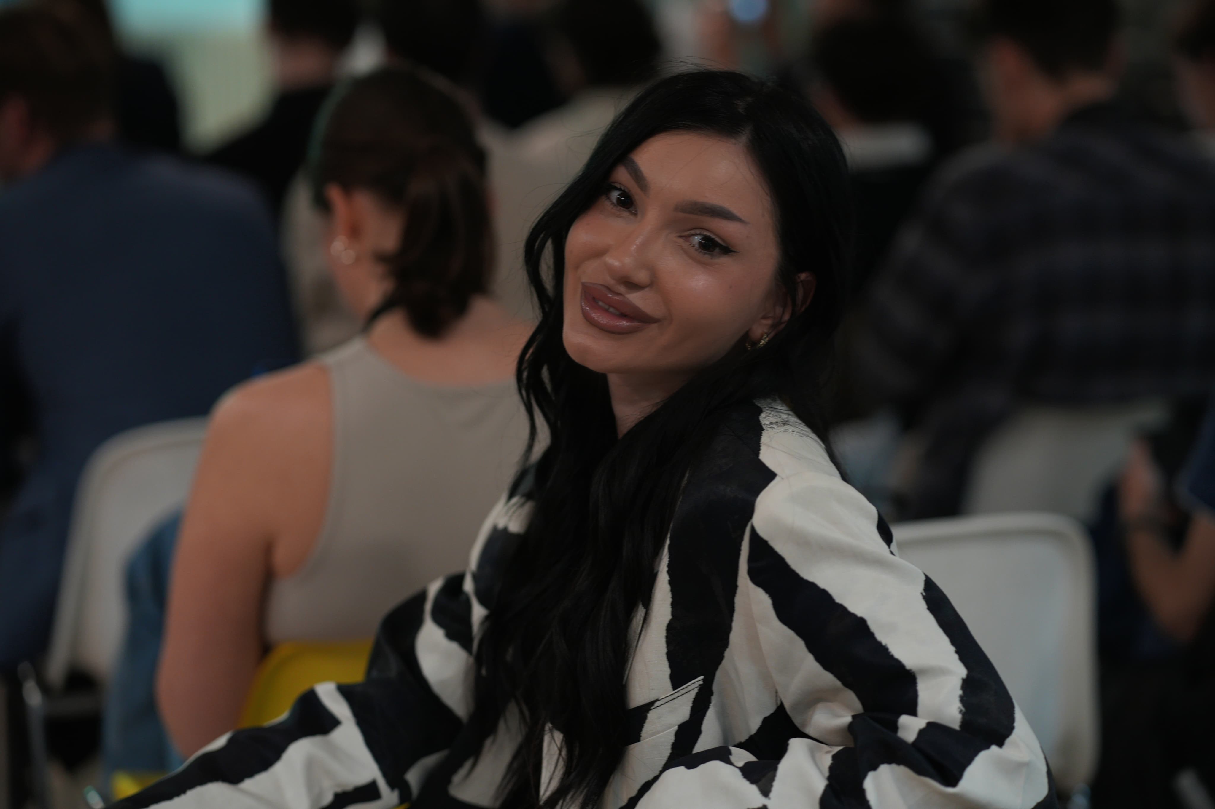 a female, with black hair and white and black clothes, smiling