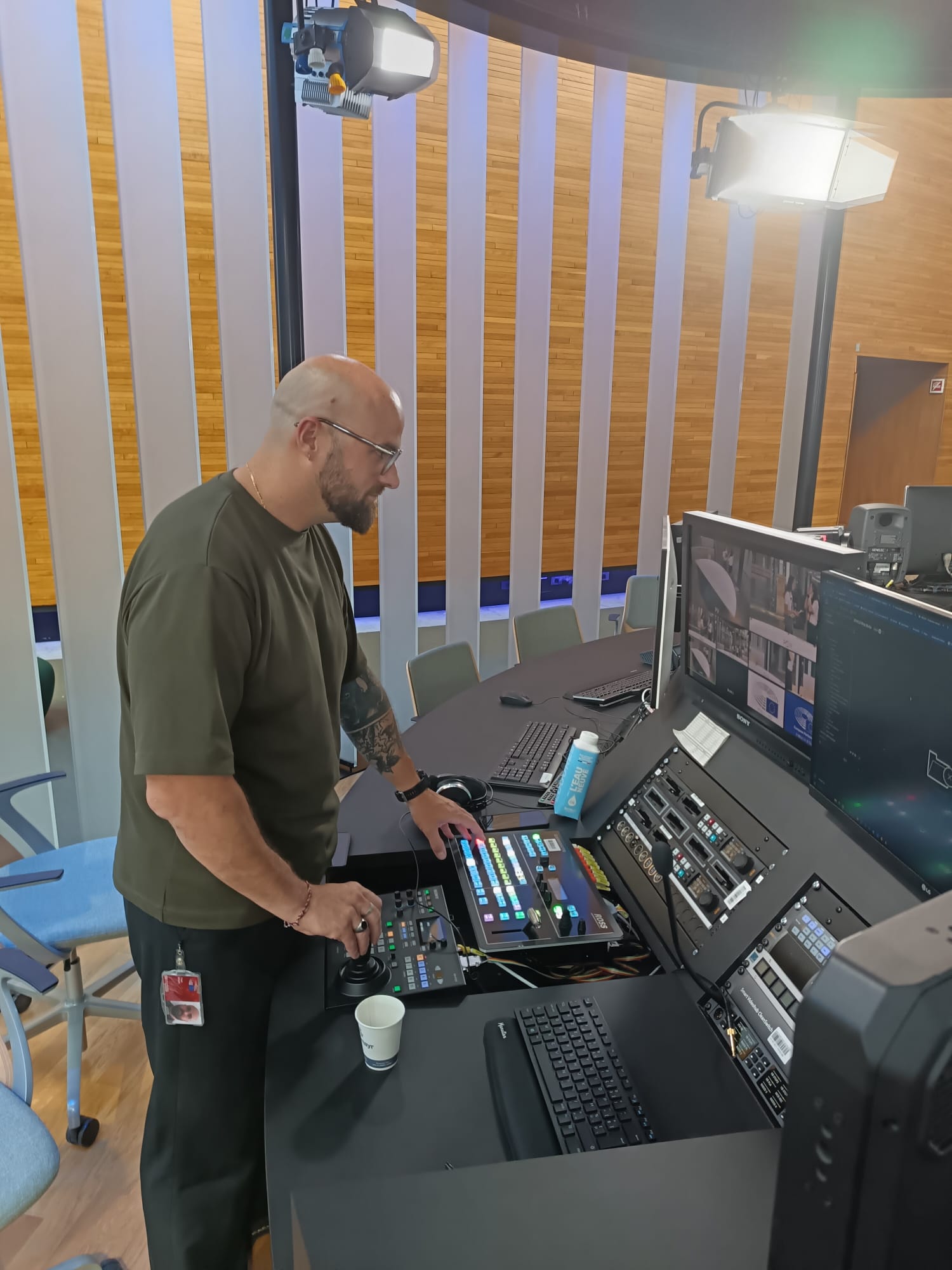 Man operating video control panel in a studio with monitors and lights.