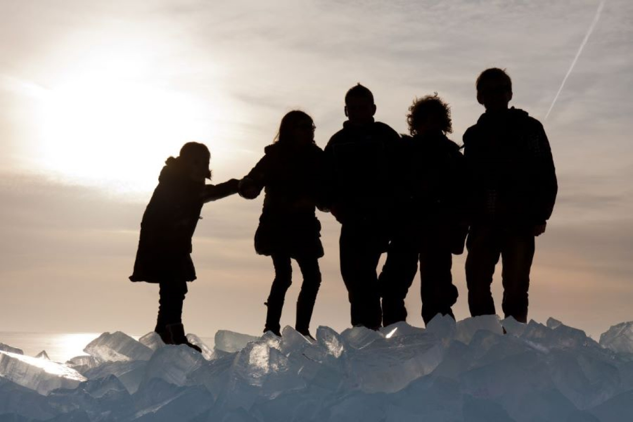 silhouettes of 5 people standing on a glacier