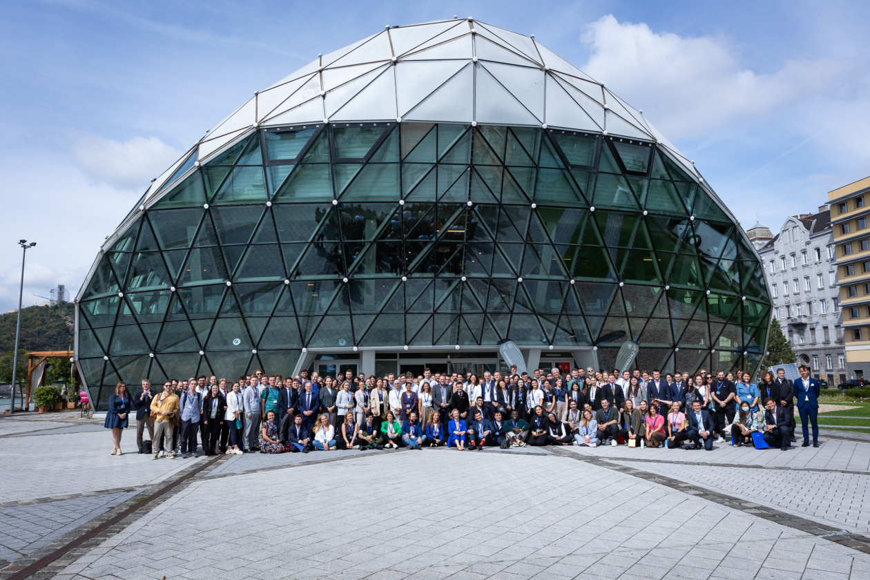 Large group of people standing outside of a modern, glass building