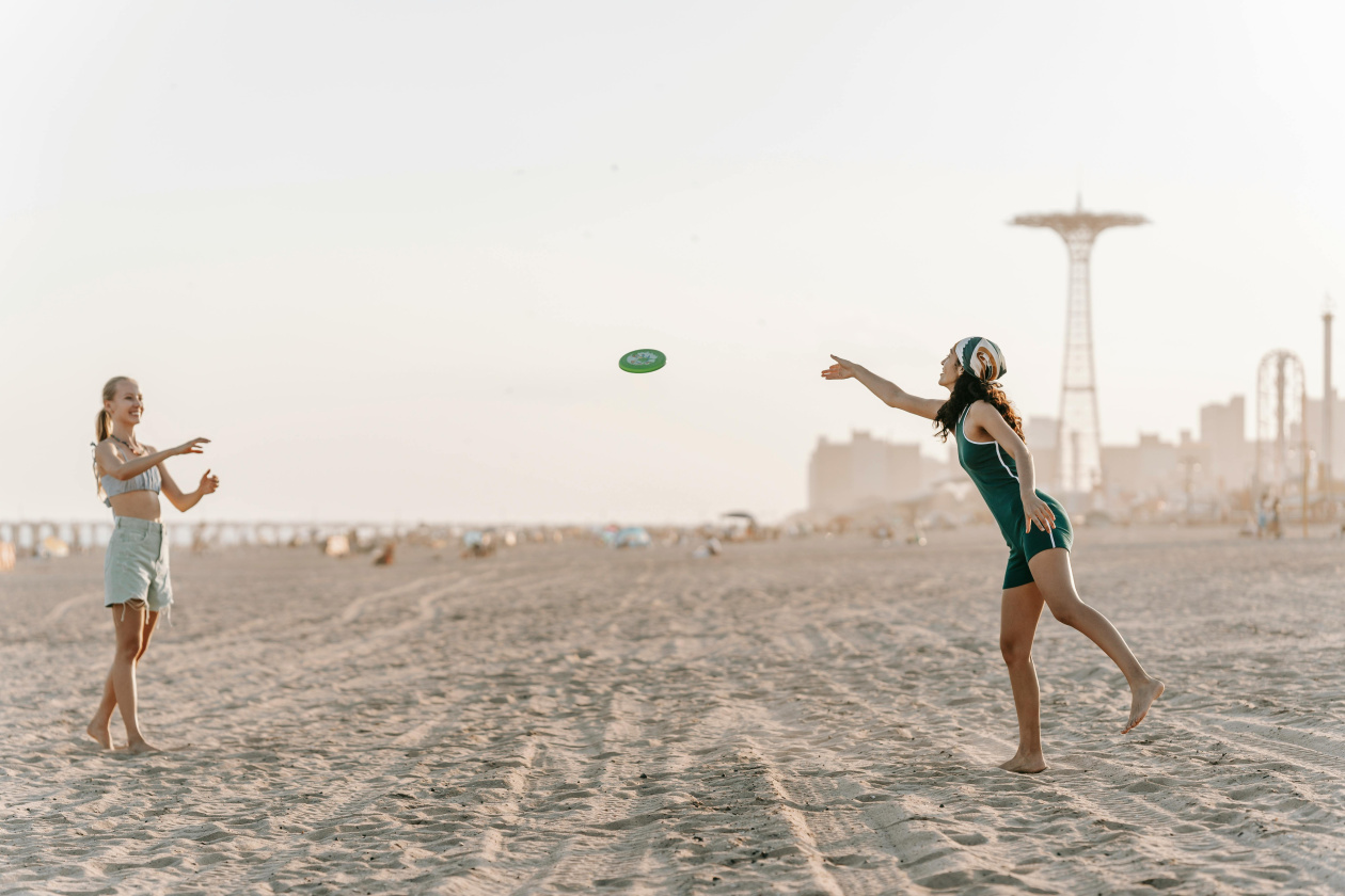 Two women playing frisbee on the beach