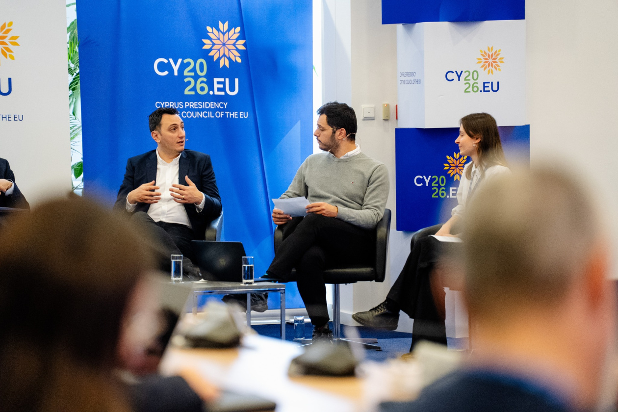 Three people in a panel discussion, with “CY2026.EU” banners indicating Cyprus Presidency of the Council of the EU in the background.
