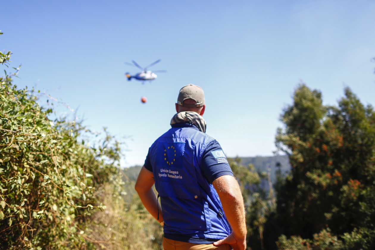 A member of the ECHO delegation watching an helicopter from the National Forestry Corporation (Conaf) dropping water on the fire in Concepción