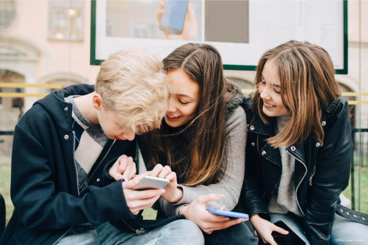 Three children looking at a smart phone