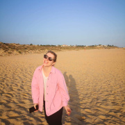 A photo of Eva on the beach in a pink jacket