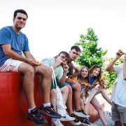 Group of young people sitting besides one another looking very happy
