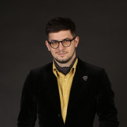 A young man wearing glasses and a yellow shirt.