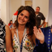 Young girl at an event smiling and looking at the camera. She seems happy and friendly.