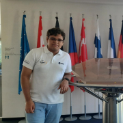 Vincent at a display of all the flags of the ESO members and a glass replica of an ELT mirror piece engraved with the signatures of each Head of State marking the conception of the ELT.