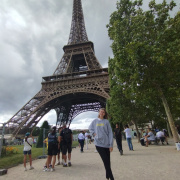 A girl standing in fron of the Eiffel Tower.
