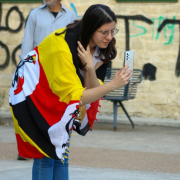 Niki Koutsoftides wearing a scuff of Ugandan flag print, taking a picture at Running-Fluent Initiative’s intercultural exchange event