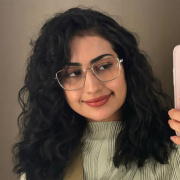 Bild på Omaima som tar en bild med sin mobiltelefon i en spegel, ler och tittar in i telefonen.