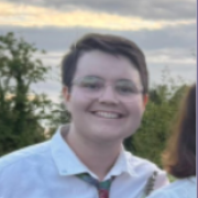 Photo of Clément after 10 months in Belgium, smiling. Cloudy background.